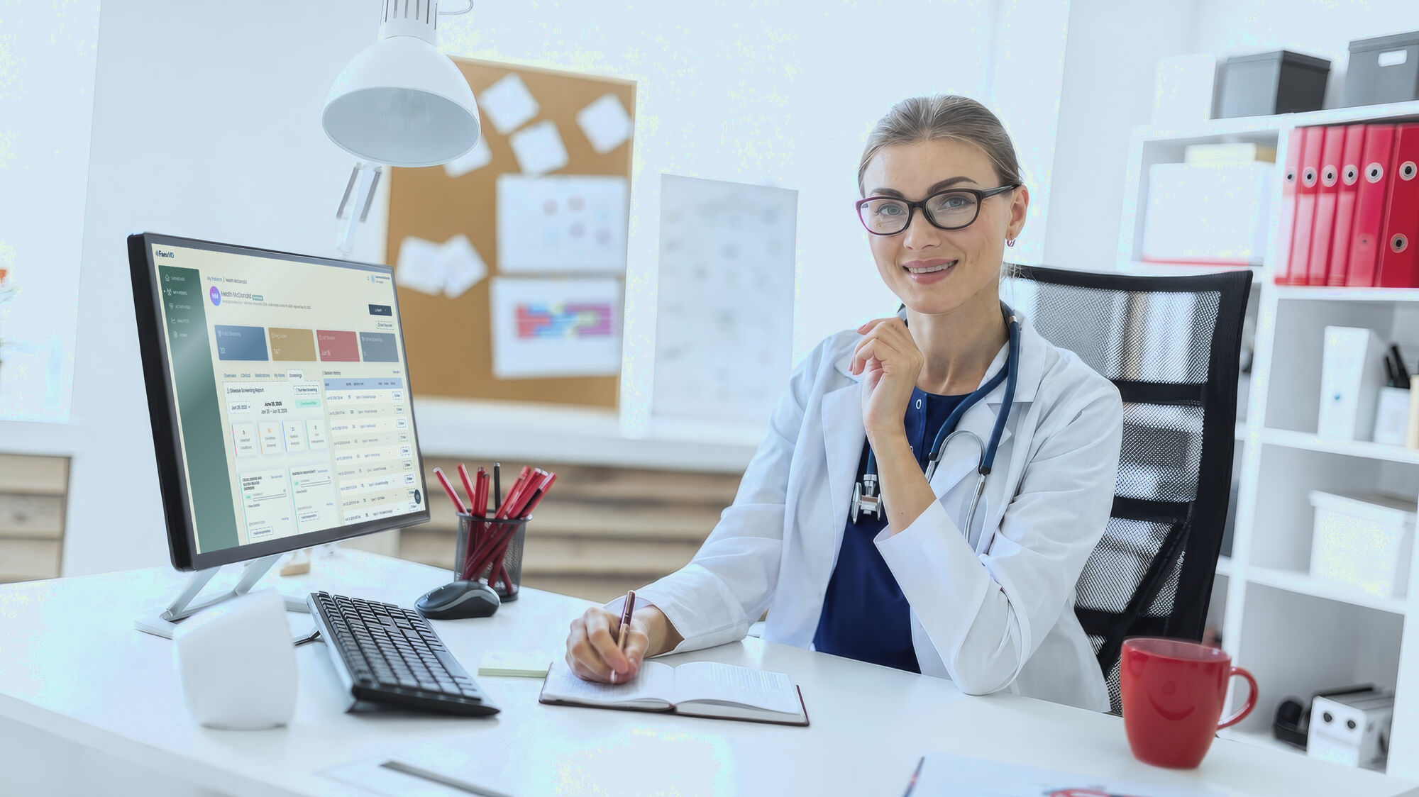 A clinician at a desk taking notes, with the Faex MD dashboard on the monitor beside her