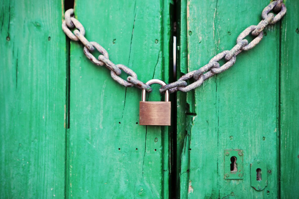 A rustic green wooden door secured with a heavy chain and padlock, symbolizing security.